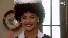 a woman with curly hair is wearing a maid hat and smiling