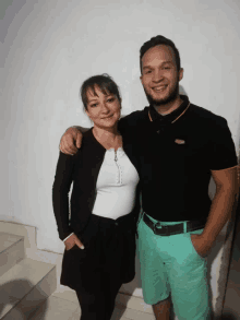 a man and a woman posing for a picture with the man wearing a black polo shirt