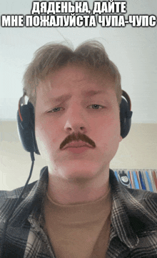 a man with a mustache wearing headphones and a plaid shirt has a meme on his face