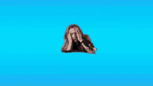 a woman is holding her head in pain while laying on a blue background .