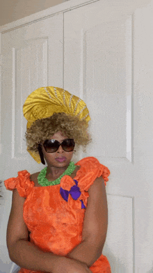 a woman wearing an orange dress and sunglasses stands in front of a door