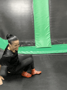 a woman is sitting on a trampoline with a green cushion