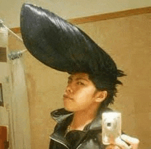 a man is taking a selfie in front of a mirror while wearing a large hat .