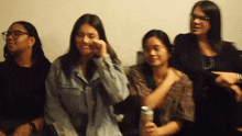 a group of women are sitting in a row and one of them is holding a can of soda .