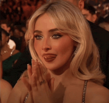 a blonde woman with a ring on her finger is clapping her hands
