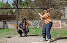 a boy is swinging a baseball bat while a catcher watches .