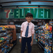 a young boy stands in front of a 7 eleven sign