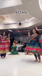 a group of women in colorful dresses are dancing in a room with the word attan above them