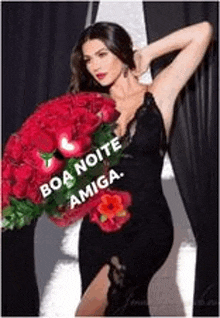 a woman in a black dress is holding a large bouquet of red flowers .