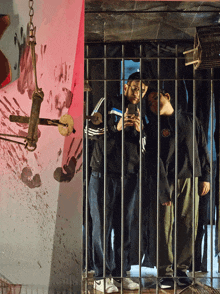 a group of men behind bars with one wearing a black shirt with the word adidas on it