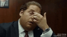 a man in a suit and tie is rubbing his face