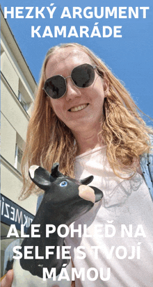 a woman wearing sunglasses is holding a black cow head