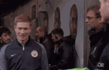 a group of men are standing next to each other in front of a wall with portraits of soccer players on it .