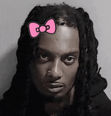 a man with dreadlocks is wearing a hello kitty bow tie on his head .