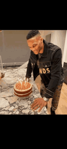 a man wearing a nds shirt is cutting a cake