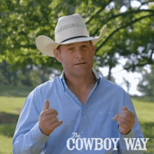 a man wearing a cowboy hat giving a thumbs up in front of a sign that says the cowboy way