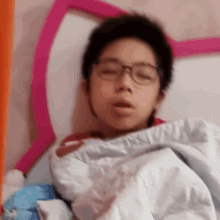 a young boy wearing glasses is sleeping in a bed