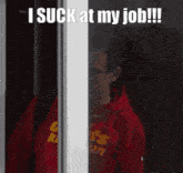 a man wearing a red shirt that says ' i suck at my job '