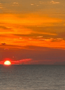 a sunset over the ocean with a bright orange sky