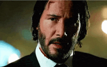 a close up of a man with a beard wearing a suit and tie with a bloody face .