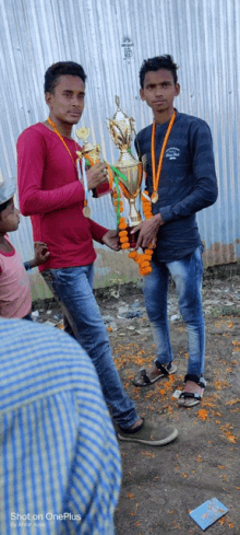 two young men are standing next to each other holding trophies and medals around their necks .