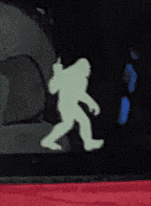 a glow in the dark silhouette of a bigfoot walking in the dark