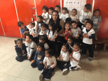 a group of children are posing for a picture with a woman wearing a shirt that says ' a ' on it