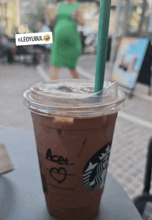 a starbucks cup with a green straw has the word acet written on it