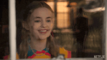 a girl is smiling while looking out of a window with netflix written on the bottom