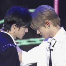 two men are standing next to each other on a stage and touching each other 's foreheads .