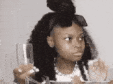 a little girl is holding a glass of wine and a knife .
