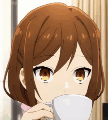 a girl with brown hair drinking from a white cup