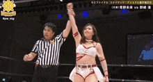 a female wrestler holds her fist up in the air in front of a referee with a star on it