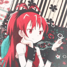 a girl with long red hair is sitting on a striped blanket .
