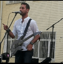 a man is singing into a microphone while playing a guitar