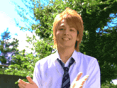 a young man wearing a white shirt and tie is clapping his hands