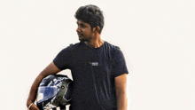 a man in a black t-shirt holds a motorcycle helmet in his right hand