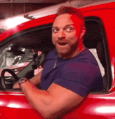a man is sitting in a red car with his mouth open