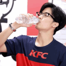 a man drinking water from a bottle with the kfc logo on it