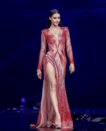 a woman in a red dress with a high slit walks down a runway