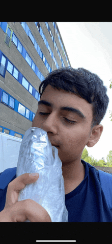 a young man is eating a burrito outside in front of a building