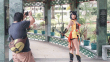 a man is taking a picture of a woman in a costume in front of a sign that says ' chinese '