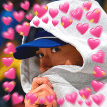 a man wearing a hoodie and a blue hat with pink hearts around him