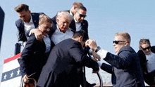 a group of men in suits are pushing a man in a wheelchair .