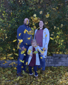 a family is posing for a picture with leaves flying around them