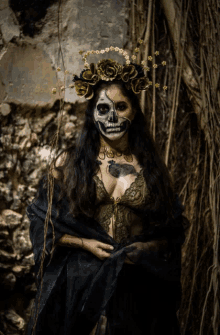 a woman with a skull painted on her face has a crown of flowers on her head