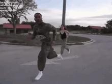 a man in a military uniform is running with a woman behind him