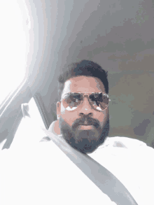 a man with a beard wearing sunglasses and a white shirt