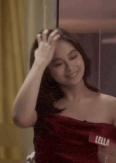 a woman in a red dress is smiling and touching her hair while sitting in front of a mirror .