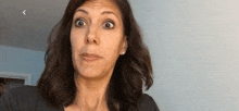 a woman is making a funny face while wearing earrings and a gray shirt .